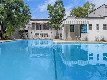 Castle Hills apartment for rent - A swimming pool in front of a building with a white exterior and a blue signboard.