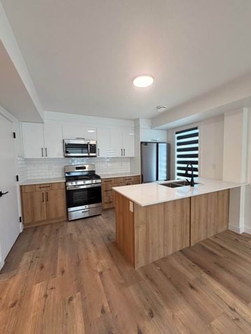 Edmonton apartment for rent - A modern kitchen with wooden floors and white cabinets.