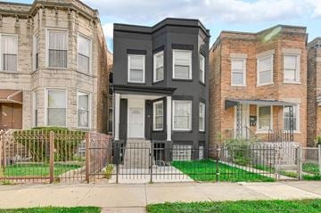 Chicago apartment for rent - A black two-story house is in the middle of a row of houses.