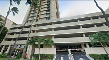 Honolulu apartment for rent - A parking garage with a building in the background.