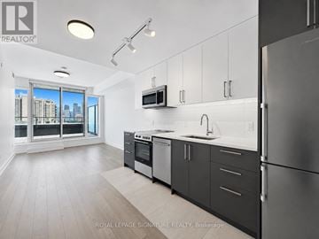 Toronto (University) condo for rent - A modern kitchen with a refrigerator, oven, and microwave.