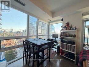 Toronto (Moss Park) condo for rent - A dining room with a table and chairs and a view of the city.