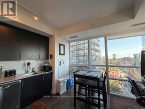 Toronto (Moss Park) condo for rent - A kitchen with a refrigerator, sink, and a dining table with chairs.