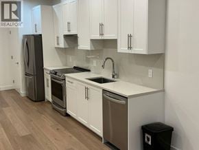 North Vancouver apartment for rent - A kitchen area with a fridge, sink and trash bin.
