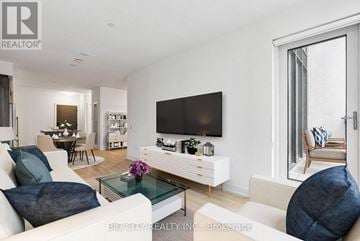 Toronto (Banbury-Don Mills) condo for rent - A living room with a white couch and a flat screen TV mounted on the wall.