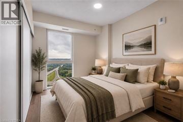 Brantford condo for rent - A bedroom with a large bed and a view of a winding road through the hills.