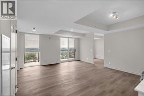 Brantford condo for rent - A spacious room with wooden floors and a sliding glass door leading to a balcony.