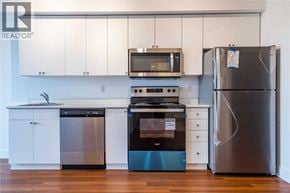 Brantford condo for rent - A kitchen with a stainless steel refrigerator, a black microwave, a black oven, and a black dishwasher.