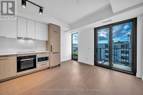 Toronto (Forest Hill South) condo for rent - A modern kitchen with wooden cabinets and a view of the city through the glass doors.