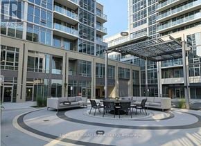 Milton (Tm Timberlea) apartment for rent - A modern outdoor seating area with a table and chairs is surrounded by glass buildings.