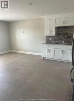 Windsor apartment for rent - A kitchen with white cabinets and a stone backsplash.