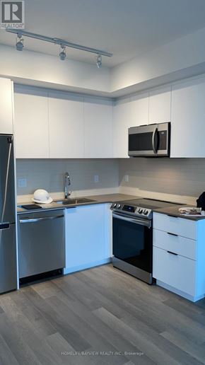 Toronto (Moss Park) condo for rent - A modern kitchen with white cabinets and stainless steel appliances.