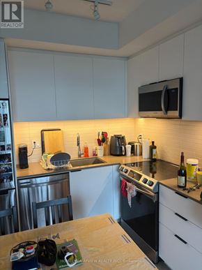 Toronto (Moss Park) condo for rent - A kitchen with white cabinets and a black microwave.