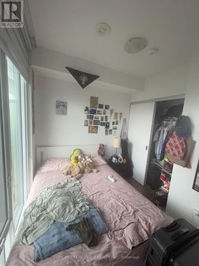 Toronto (Moss Park) condo for rent - A bedroom with a bed, a suitcase, and a wall with pictures and a mirror.