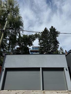 Toronto (North Riverdale) apartment for rent - A grey garage door is closed and there is a tree in front of a building.