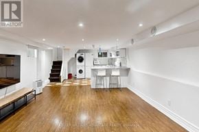 Toronto (Woodbine Corridor) apartment for rent - A spacious room with wood flooring and a washer and dryer stacked in the corner.