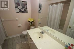 Markham (Commerce Valley) townhouse for rent - A bathroom with a sink, toilet, and a vase of flowers.