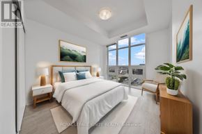 Toronto (Niagara) condo for rent - A bedroom with a large bed, a chair, and a potted plant.
