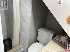 Vancouver apartment for rent - A white toilet in a small bathroom with a shower curtain.