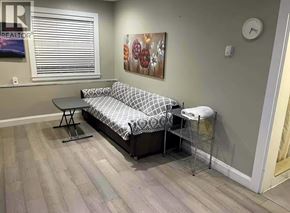 Vancouver apartment for rent - A living room with a grey sofa and a clock on the wall.