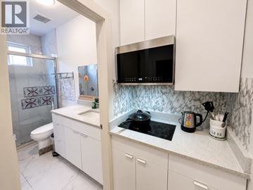 Richmond apartment for rent - A modern kitchen with white cabinets and a marble countertop.