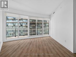 Toronto (Niagara) condo for rent - A room with wooden floors and a large window with a view of a building.