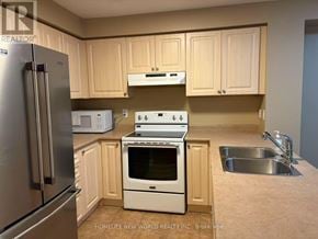 Ajax (South East) townhouse for rent - A kitchen with a stainless steel refrigerator, white oven, and a white microwave.