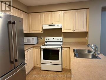 Ajax (South East) townhouse for rent - A kitchen with a stainless steel refrigerator, white oven, and a white microwave.