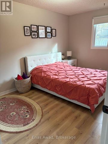 Waterloo apartment for rent - A bedroom with a bed covered in a red comforter and a white headboard.