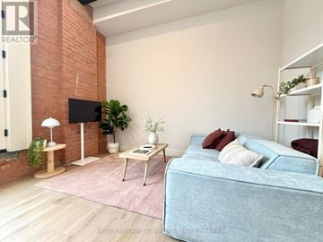 Hamilton (Central) multi-family for rent - A living room with a blue couch and a brick wall.