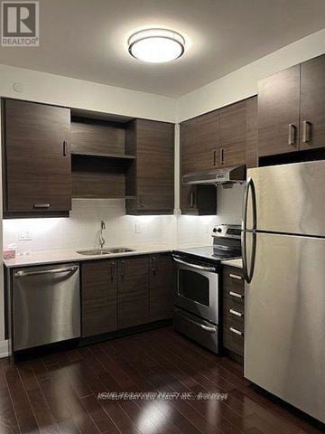 Markham (Unionville) condo for rent - A modern kitchen with dark wood cabinets and stainless steel appliances.