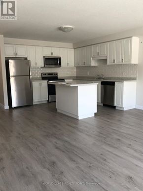 Norfolk (Simcoe) townhouse for rent - A kitchen with white cabinets and a grey floor.