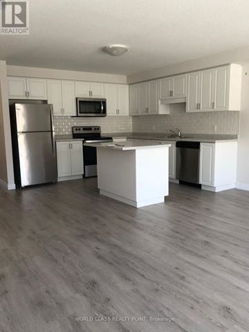 Norfolk (Simcoe) townhouse for rent - A kitchen with white cabinets and a grey floor.