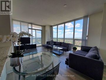 Mississauga (City Centre) condo for rent - A living room with a glass table and a view of the ocean.