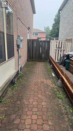 Markham (Middlefield) apartment for rent - A brick pathway leads to a wooden fence and a green trash can.