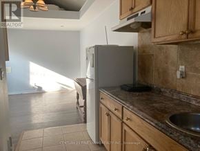 Toronto (Caledonia-Fairbank) apartment for rent - A kitchen with a refrigerator, sink, and wooden cabinets.