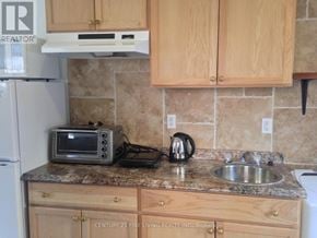 Toronto (Caledonia-Fairbank) apartment for rent - A kitchen with wooden cabinets and a granite countertop.