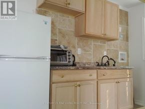 Toronto (Caledonia-Fairbank) apartment for rent - A kitchen with wooden cabinets and a white refrigerator.