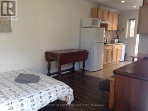 Toronto (Caledonia-Fairbank) apartment for rent - A bedroom with a bed, a table, and a refrigerator in the kitchen area.
