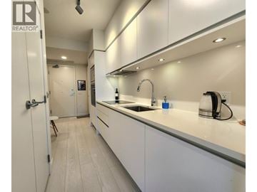 Vancouver apartment for rent - A modern kitchen with white cabinets and a sink.