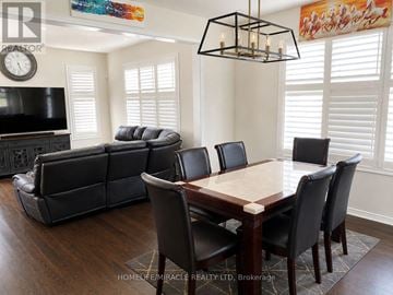 Hamilton (Binbrook) apartment for rent - A living room with a black leather couch, a wooden dining table with chairs, and a television.