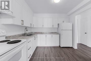 Welland (Welland Downtown) townhouse for rent - A white kitchen with a stove top oven and a refrigerator.