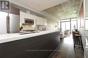 Toronto (Niagara) condo for rent - A modern kitchen with a bar stool and a refrigerator.