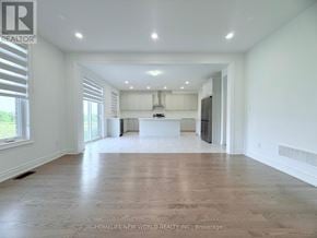 Whitchurch-Stouffville (Stouffville) apartment for rent - A spacious, empty room with a kitchen area in the background.