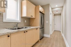 Toronto (Dovercourt-Wallace Emerson-Junction) townhouse for rent - A kitchen with wooden cabinets and a stainless steel refrigerator.