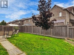 Brampton (Bram East) apartment for rent - A backyard with a wooden fence and a small tree.