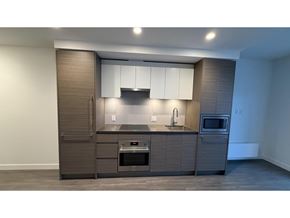 Surrey apartment for rent - A modern kitchen with a dark wood finish and white cabinets.