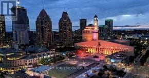 Mississauga (City Centre) condo for rent - A cityscape at dusk with a prominent building in the center.