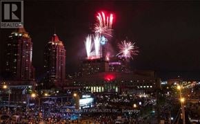 Mississauga (City Centre) condo for rent - A fireworks display lights up the night sky over a cityscape.