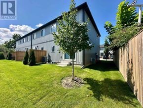St. Catharines (Oakdale) townhouse for rent - A house with a green lawn and a tree in front of it.